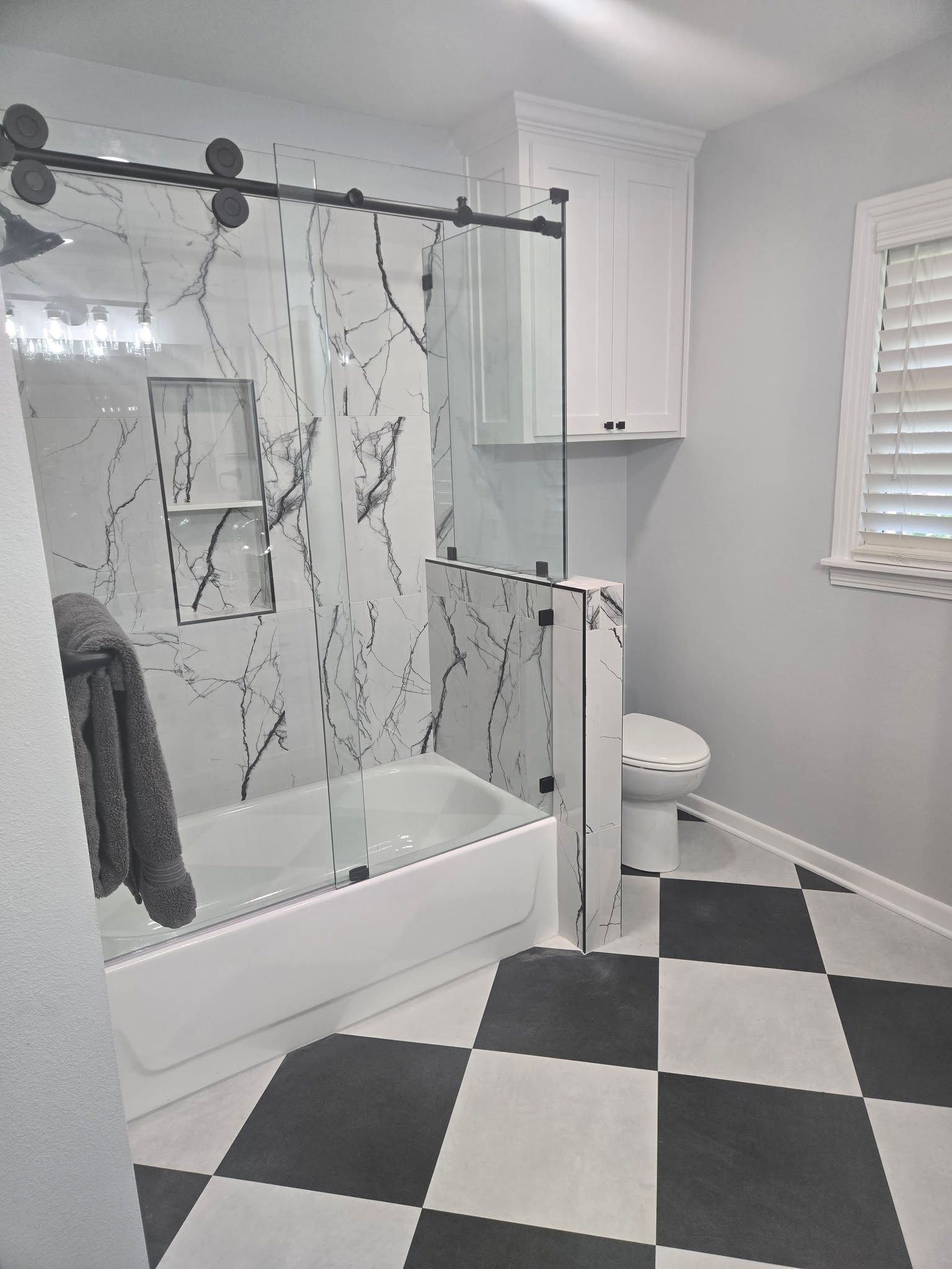 A bathroom with a bathtub , toilet , and checkered floor.