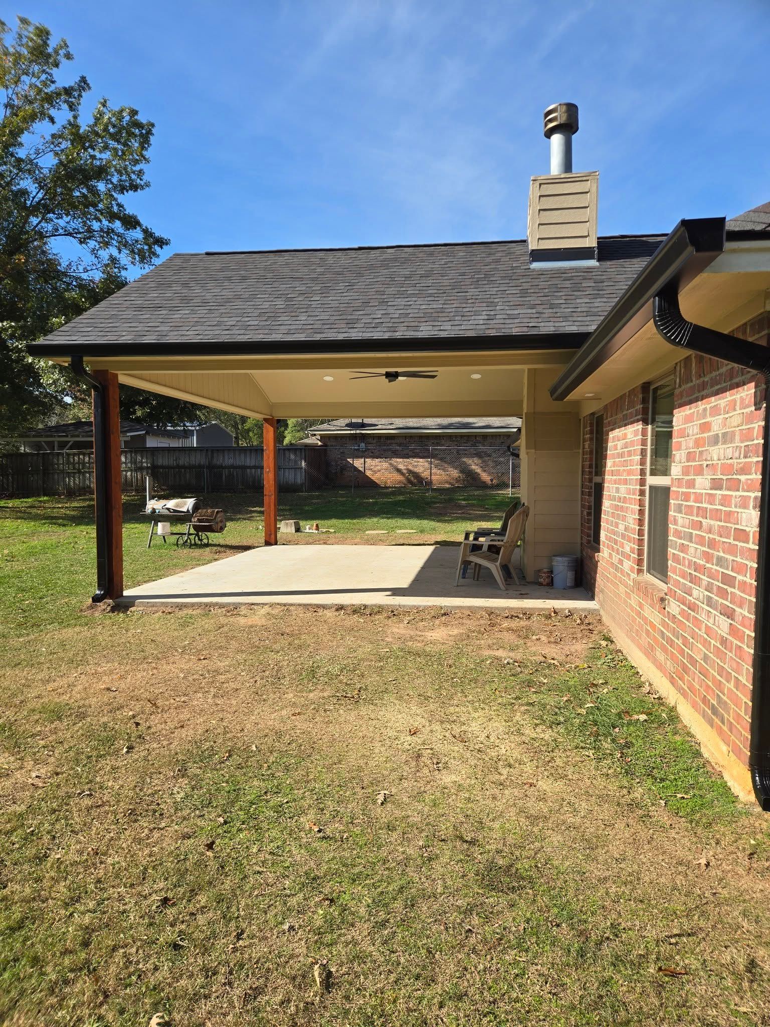 A brick house with a covered patio in the backyard.