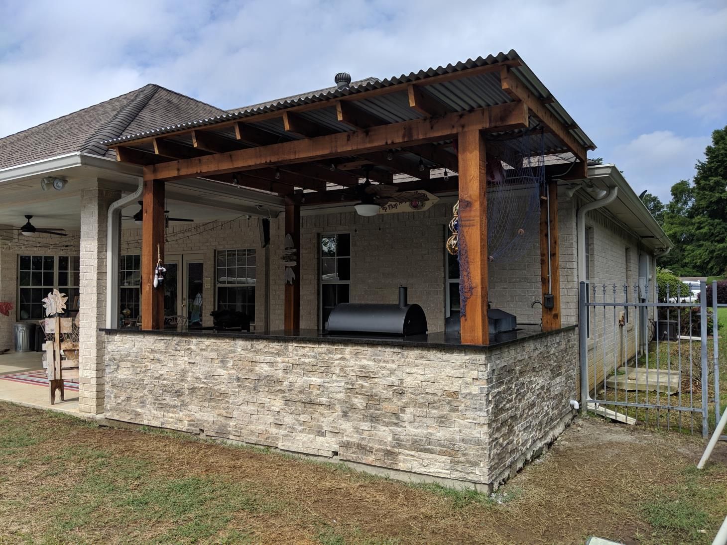 A house with a pergola and a grill in the backyard.