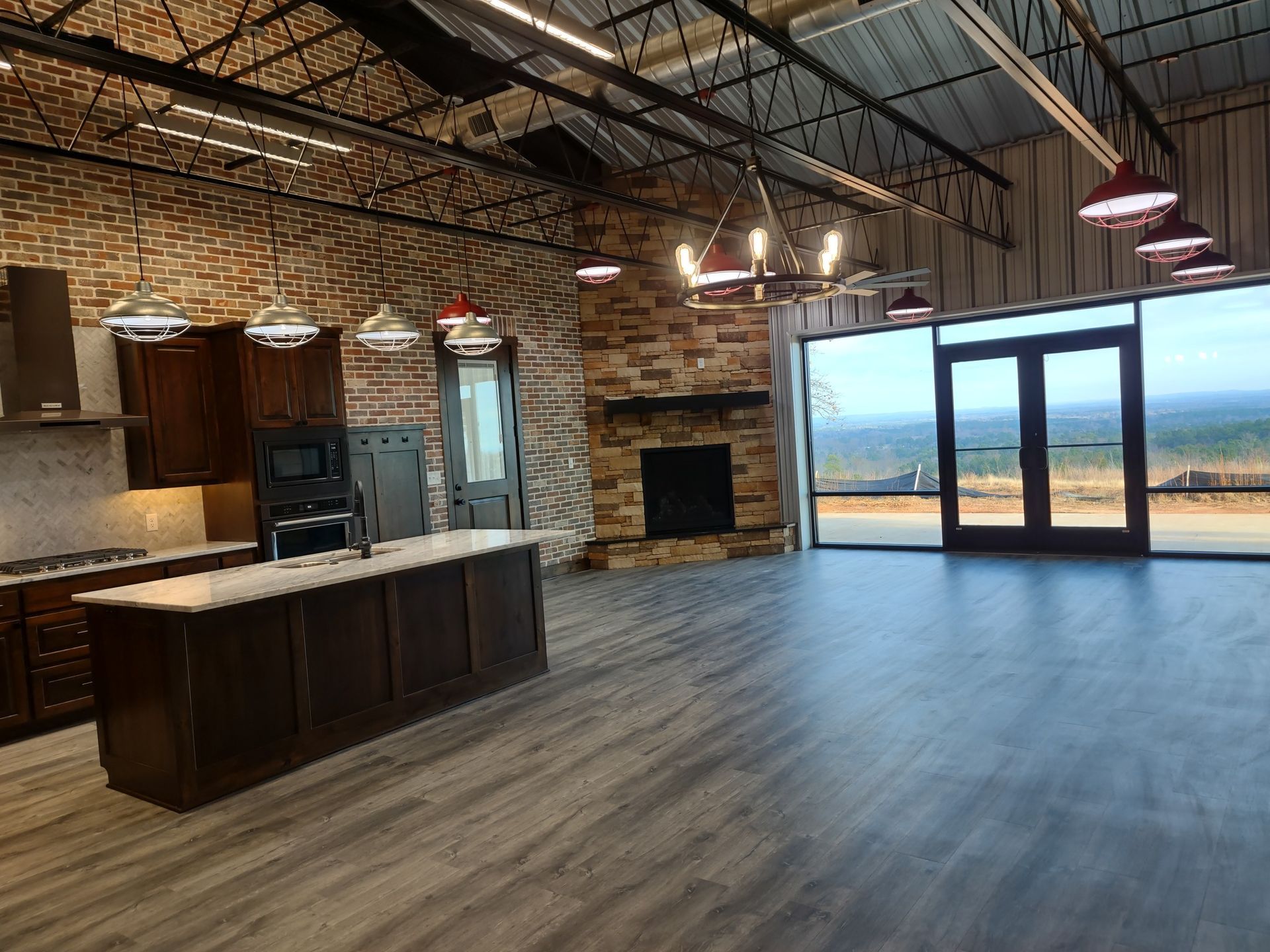 A large empty room with a kitchen , fireplace , and large windows.