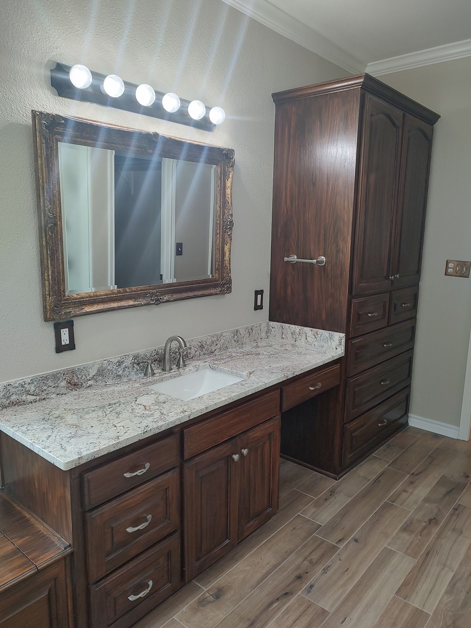 A bathroom with a sink , mirror and cabinets.