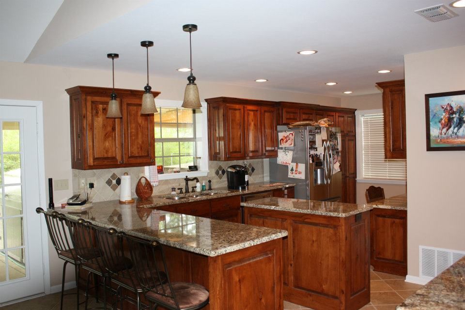 Modern kitchen with wood cabinets, granite island, pendant lights, and stainless steel appliances