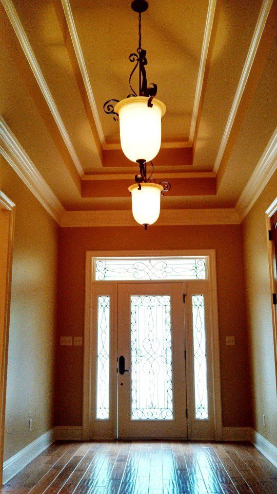 A hallway with a door and two lights hanging from the ceiling