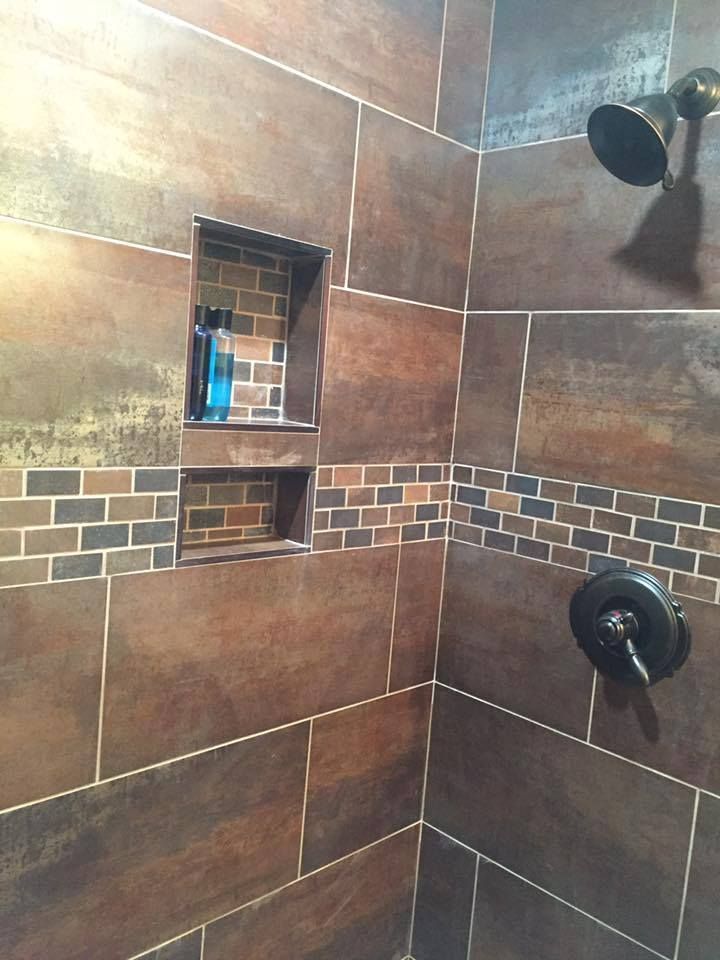 A bathroom with brown tiles and a shower head