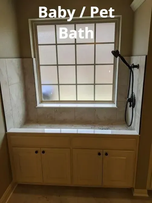 Baby and pet bath tub nook with built-in cabinet, tiled walls, and a handheld shower head