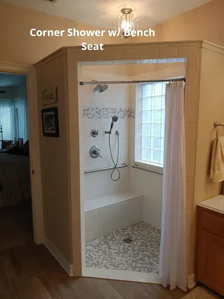 Corner shower with built-in bench seat, white tile, and glass block window.