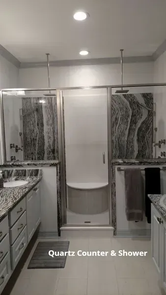 Bathroom with white quartz counter and centered shower curtain between glass sliding shower doors.