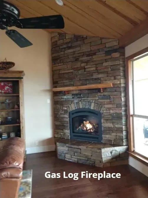 Cozy living room with stacked-stone gas log fireplace and wood mantel, burning fire