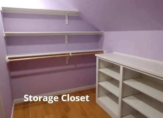 Purple storage closet with white shelves and cabinets on a wood floor