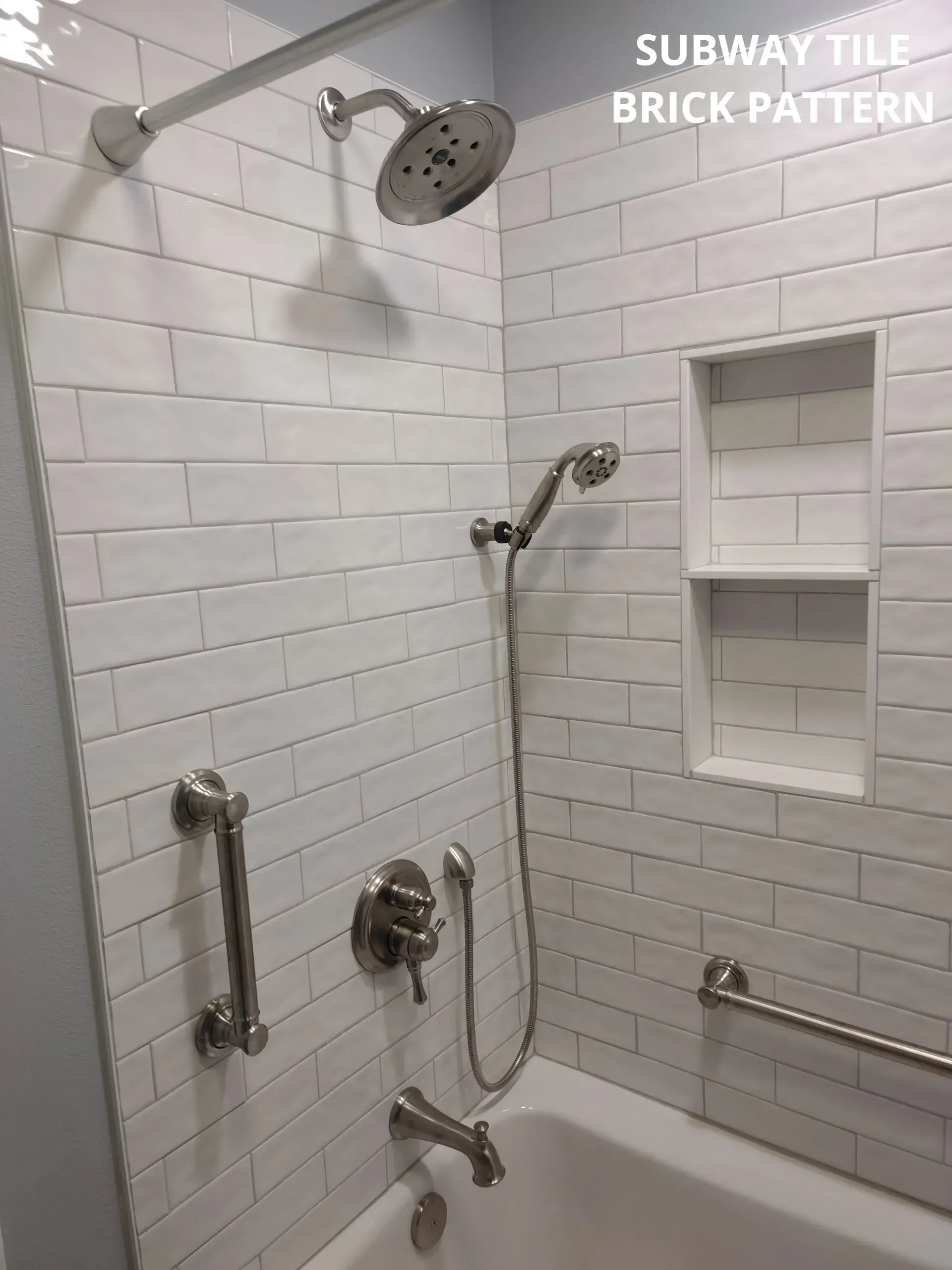 White subway-tile shower with handheld and rain showerheads, grab bars, and built-in niche shelves.