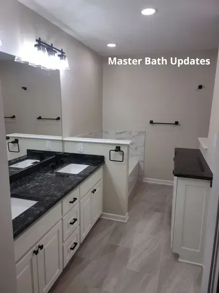 Bright master bathroom with white cabinets, black countertop, and gray floors; “Master Bath Updates” text.