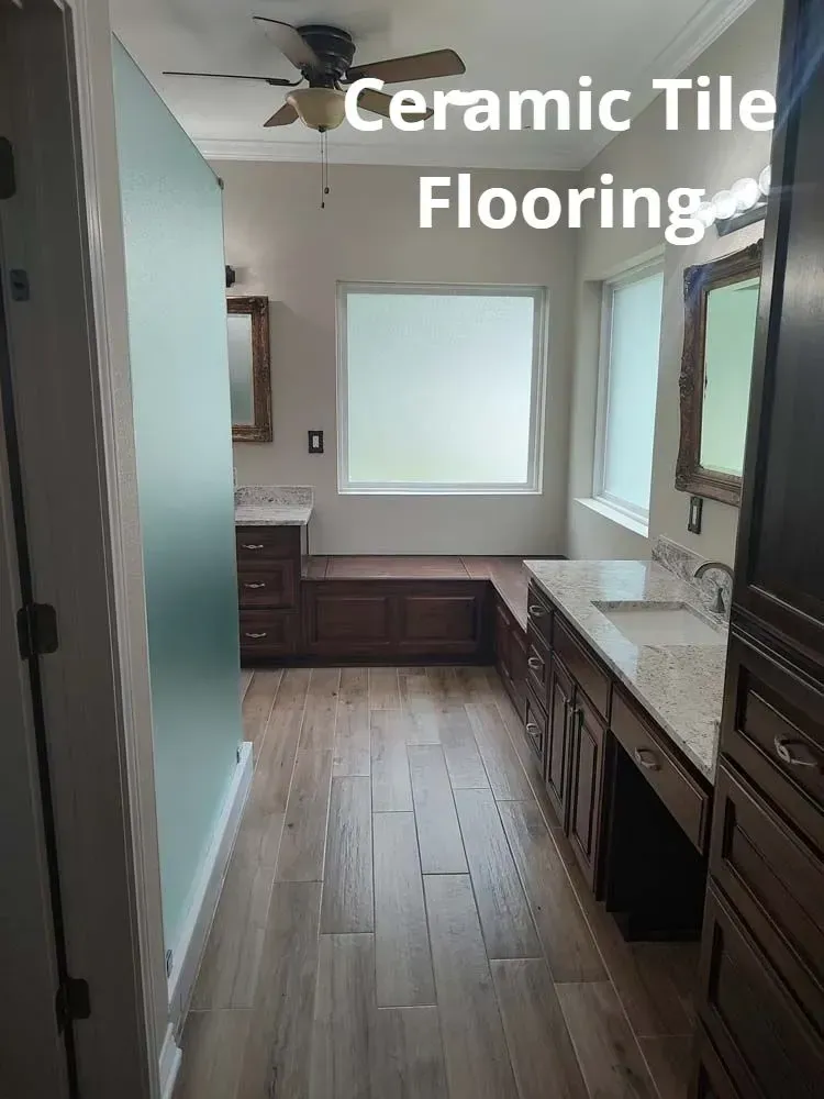 Narrow bathroom with brown ceramic tile flooring, white countertops, and a window.