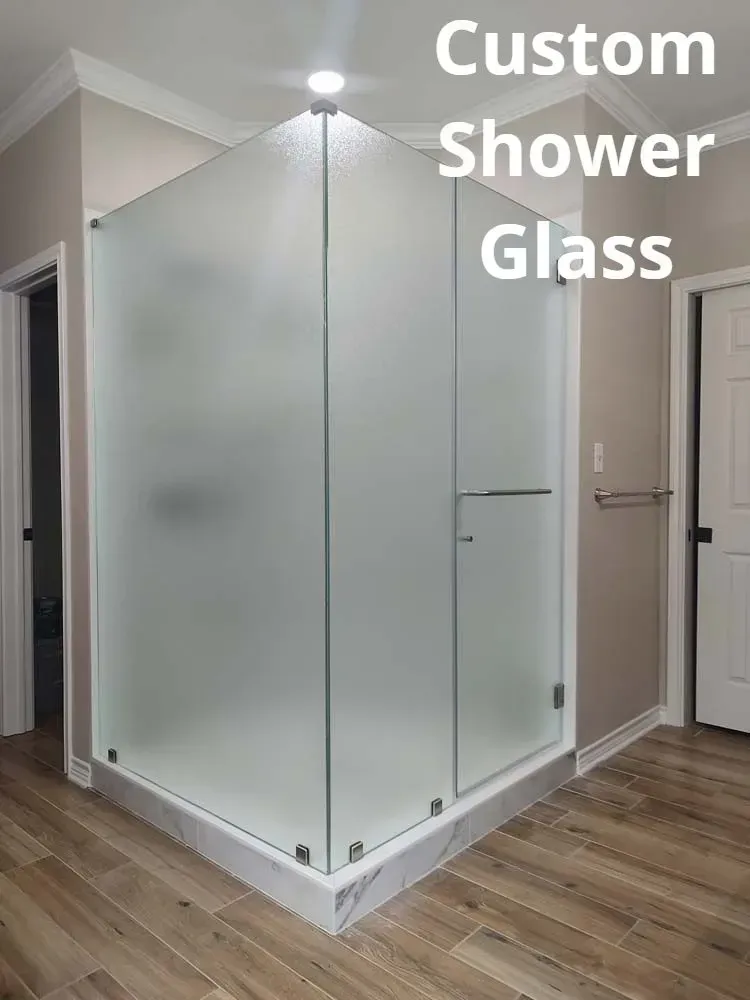 Custom glass shower enclosure in a modern bathroom with frosted panels and wood-look flooring