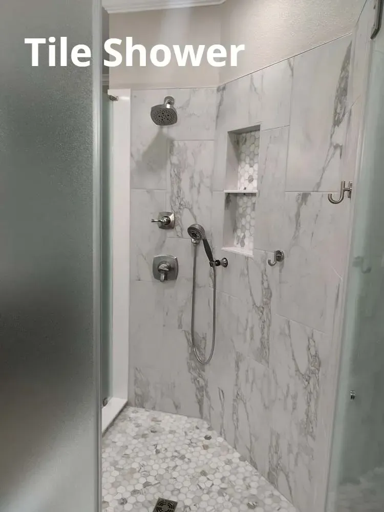Marble-tiled shower with multiple showerheads, handheld sprayer, and mosaic floor detail.