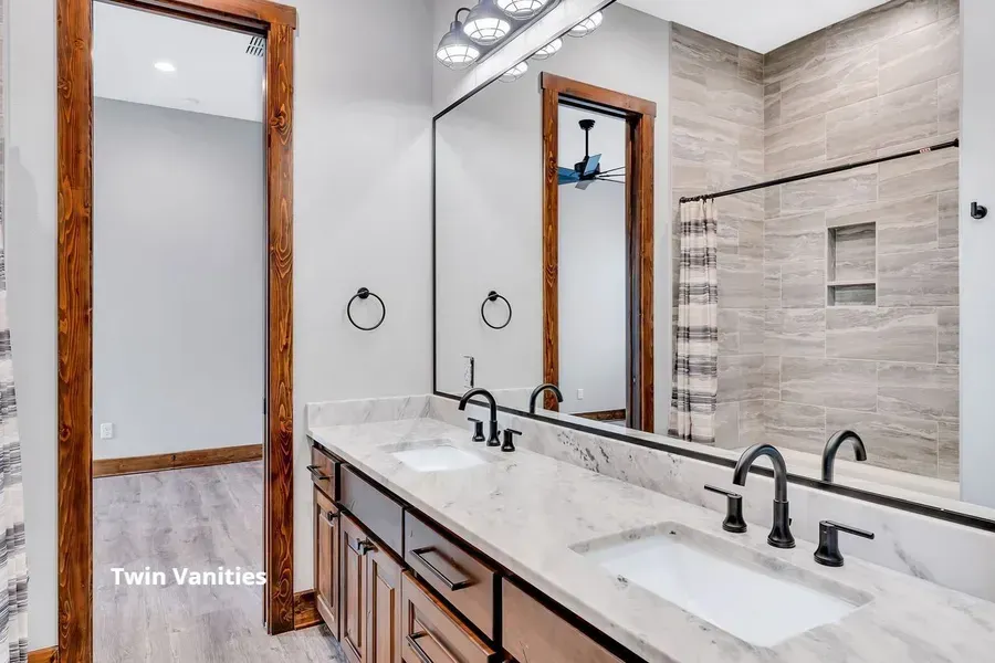 Modern bathroom with double vanity, large mirror, and beige tile shower.