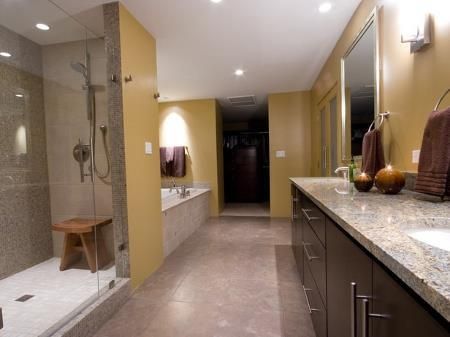 Modern bathroom with glass shower, long granite vanity, and warm recessed lighting