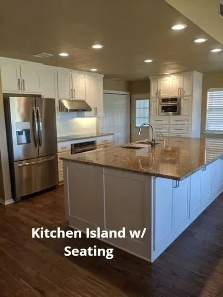 Modern kitchen with stainless appliances, white cabinets, and a large granite island with seating.