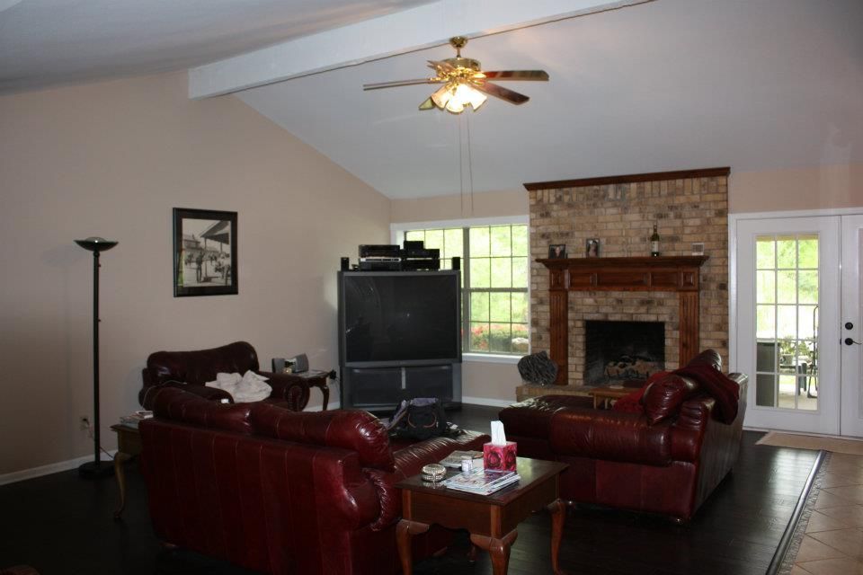 Living room with red leather chairs, TV, fireplace, ceiling fan, and glass doors