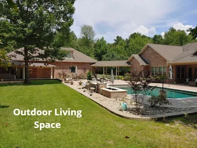 Backyard outdoor living space with pool, pergola, patio, and brick house under trees
