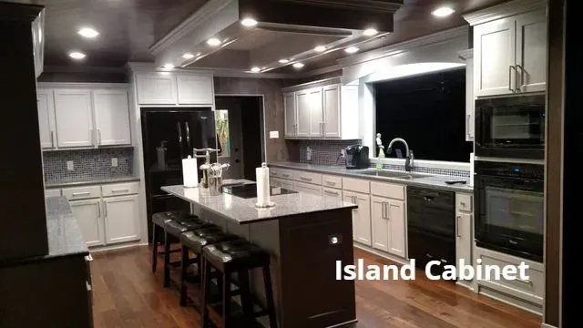 Modern kitchen with dark island, white cabinets, pendant lights, and hardwood floors