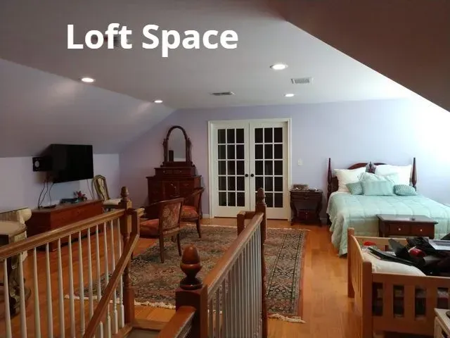 Loft bedroom with bed, TV, dresser, and French doors under sloped ceiling