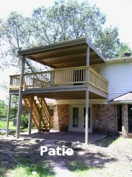 Covered wooden patio deck on the back of a house with stairs and support posts