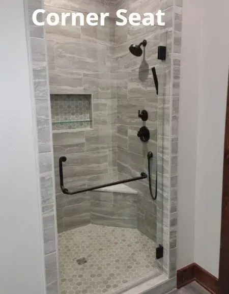 Corner shower with grab bar, built-in corner seat, and wall-mounted shower fixtures in gray tile.