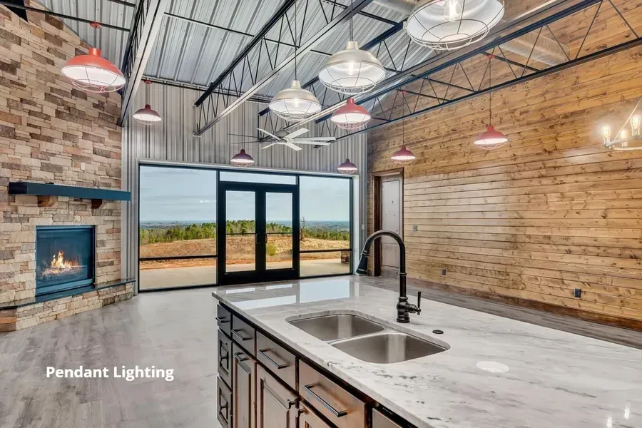Modern kitchen with marble island, pendant lights, exposed brick, and large glass doors to the outdoors