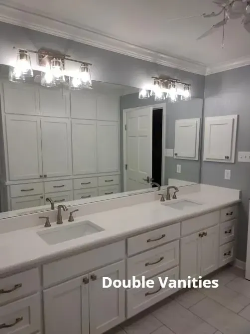 Gray bathroom with double vanity, large mirror, and white cabinets