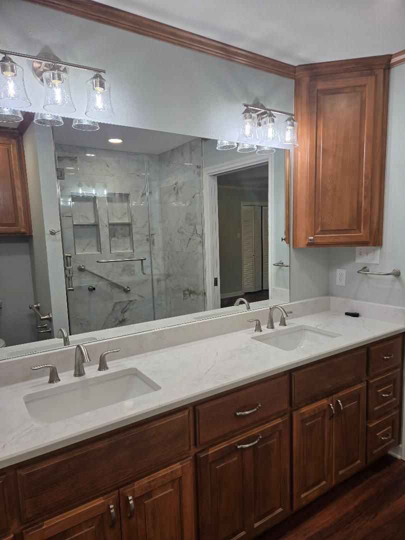 Bathroom vanity with double sinks, large mirror, and warm wood cabinets
