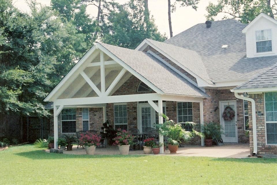Suburban brick house with front porch, gabled roof, and potted plants in a green yard