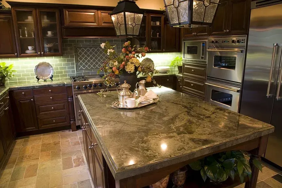 Luxurious kitchen with dark wood cabinets, granite island, and decorative centerpiece under warm lighting