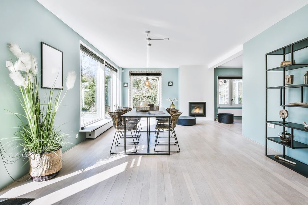 Bright modern dining room with light blue walls, large windows, and minimalist decor