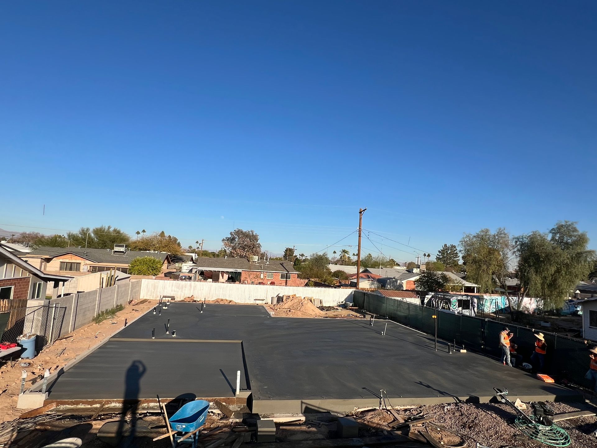 Large black tarp laid over a fenced outdoor area under a clear blue sky