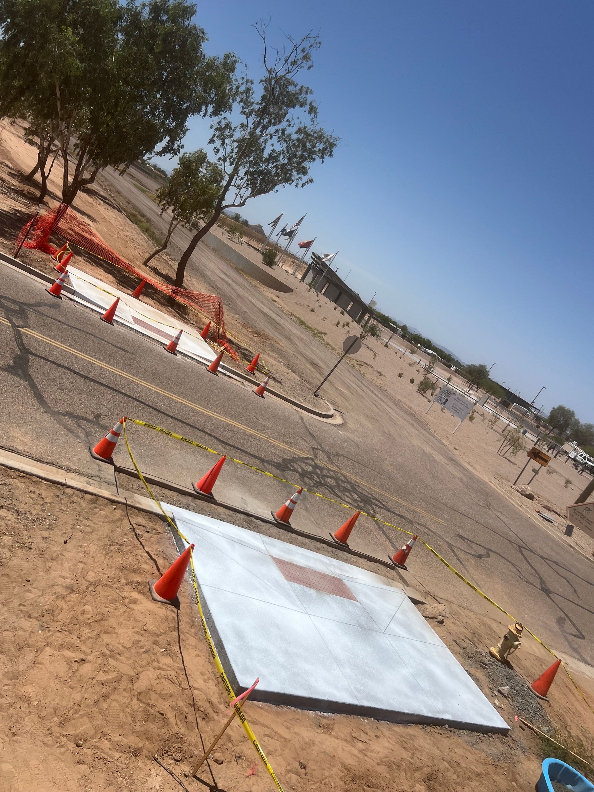 Construction site with orange cones and white panels on sandy ground under a clear blue sky