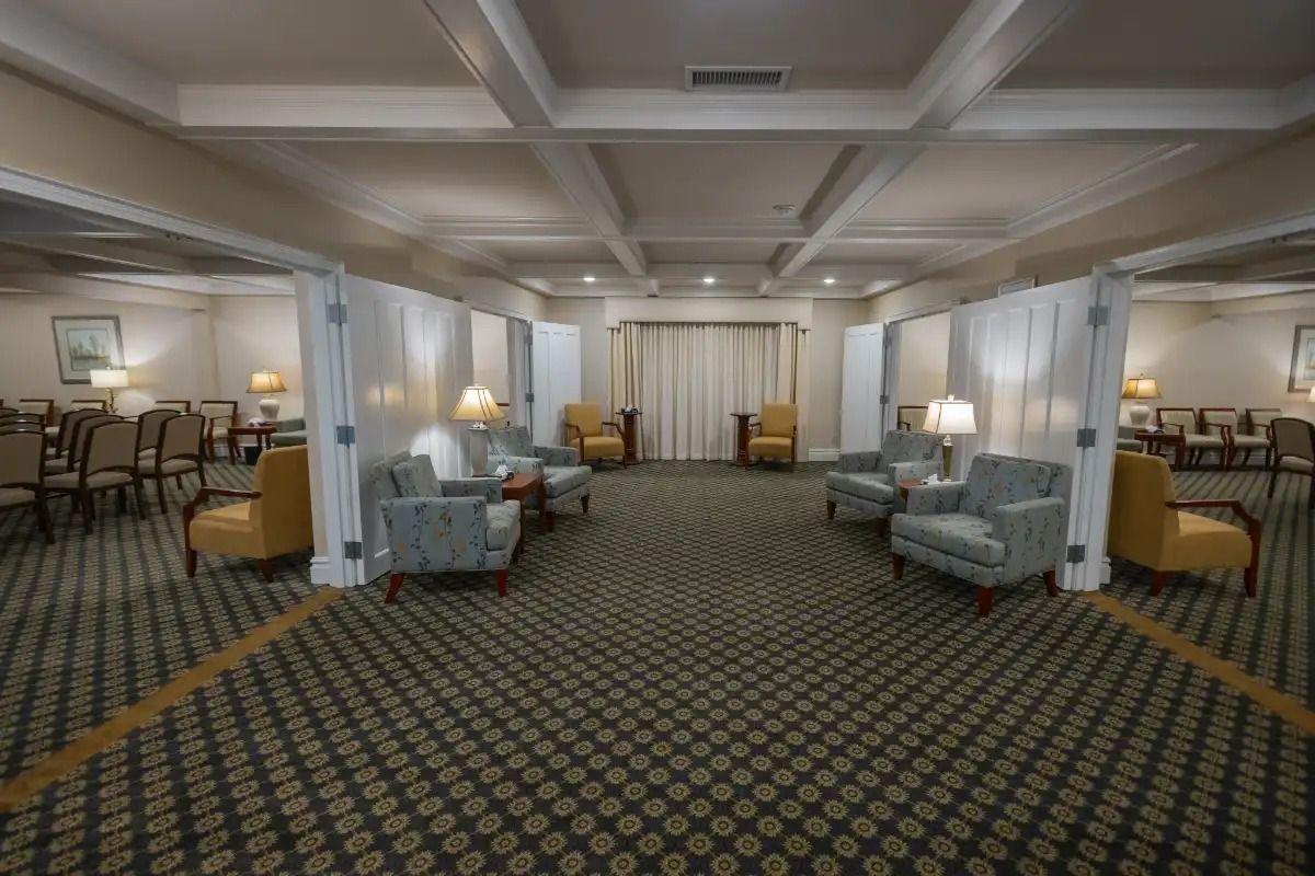 A large room with seating areas separated by partitions. Carpeted floor. Beige walls.