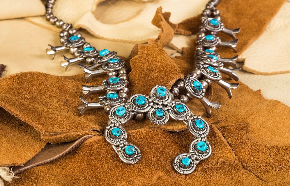 Silver necklace with turquoise stones on brown fabric
