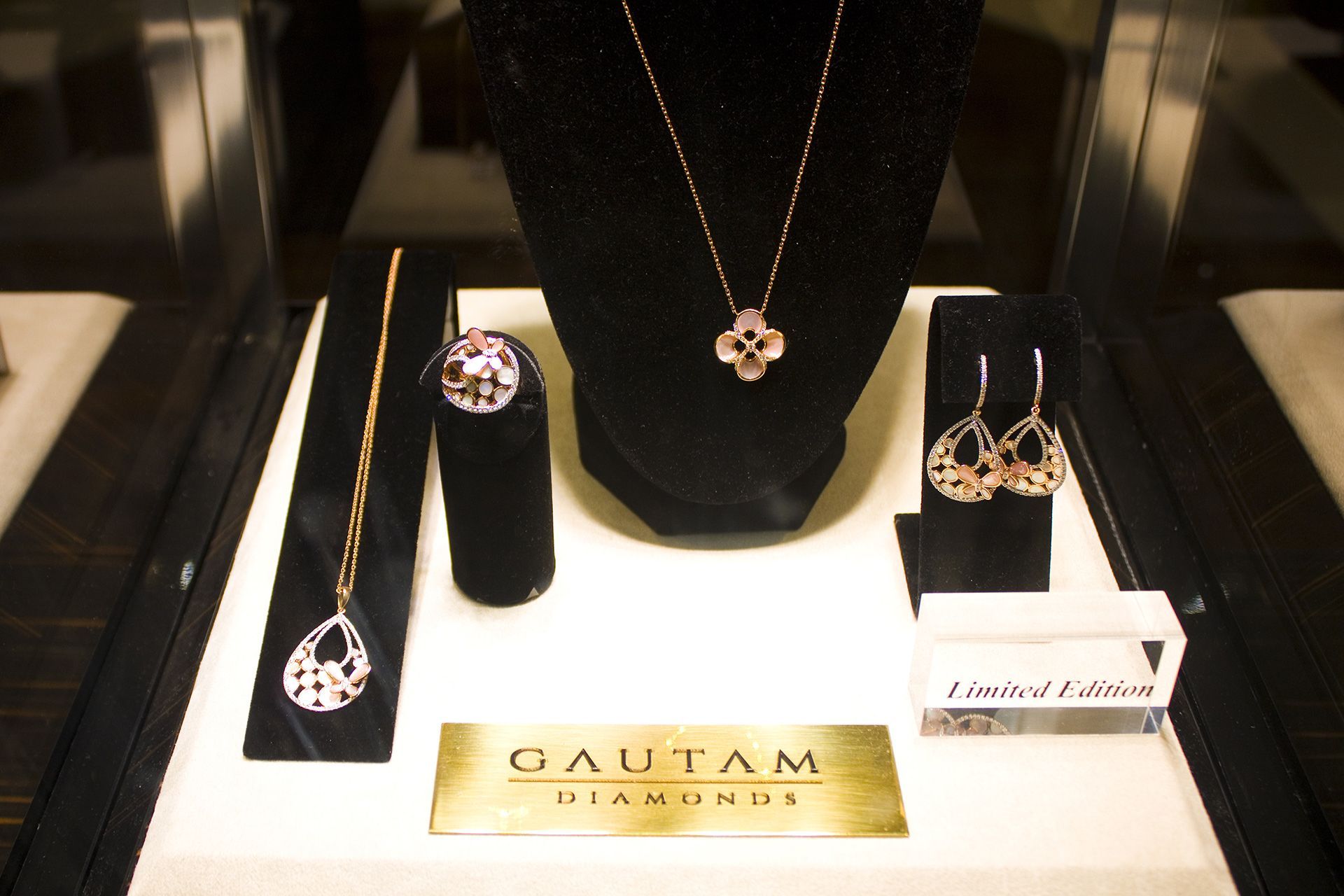 Jewelry display with diamond rings, necklace, and earrings on black stands, labeled Gautam Diamonds