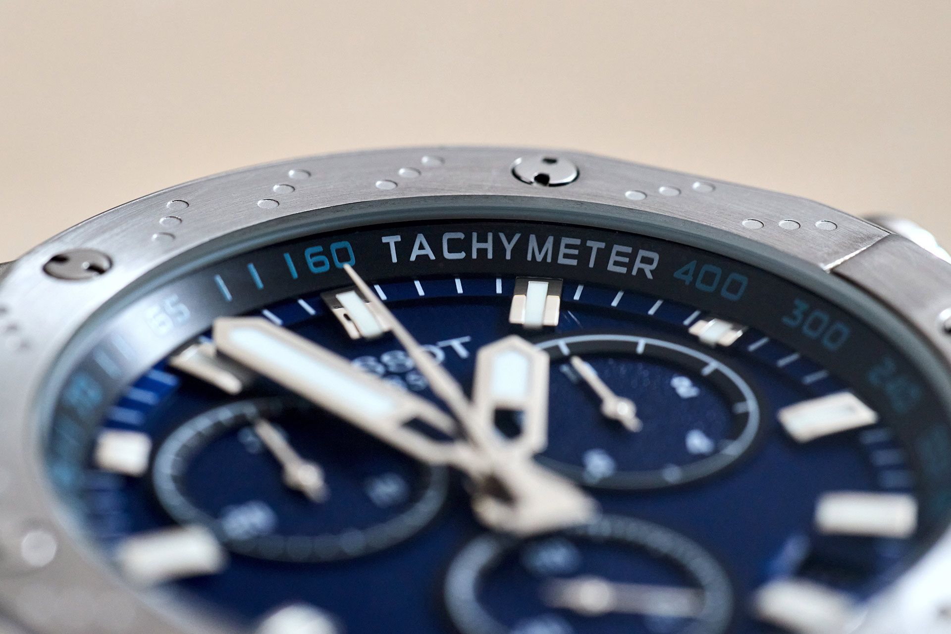 Close-up of a blue chronograph watch dial with silver hands and tachymeter bezel