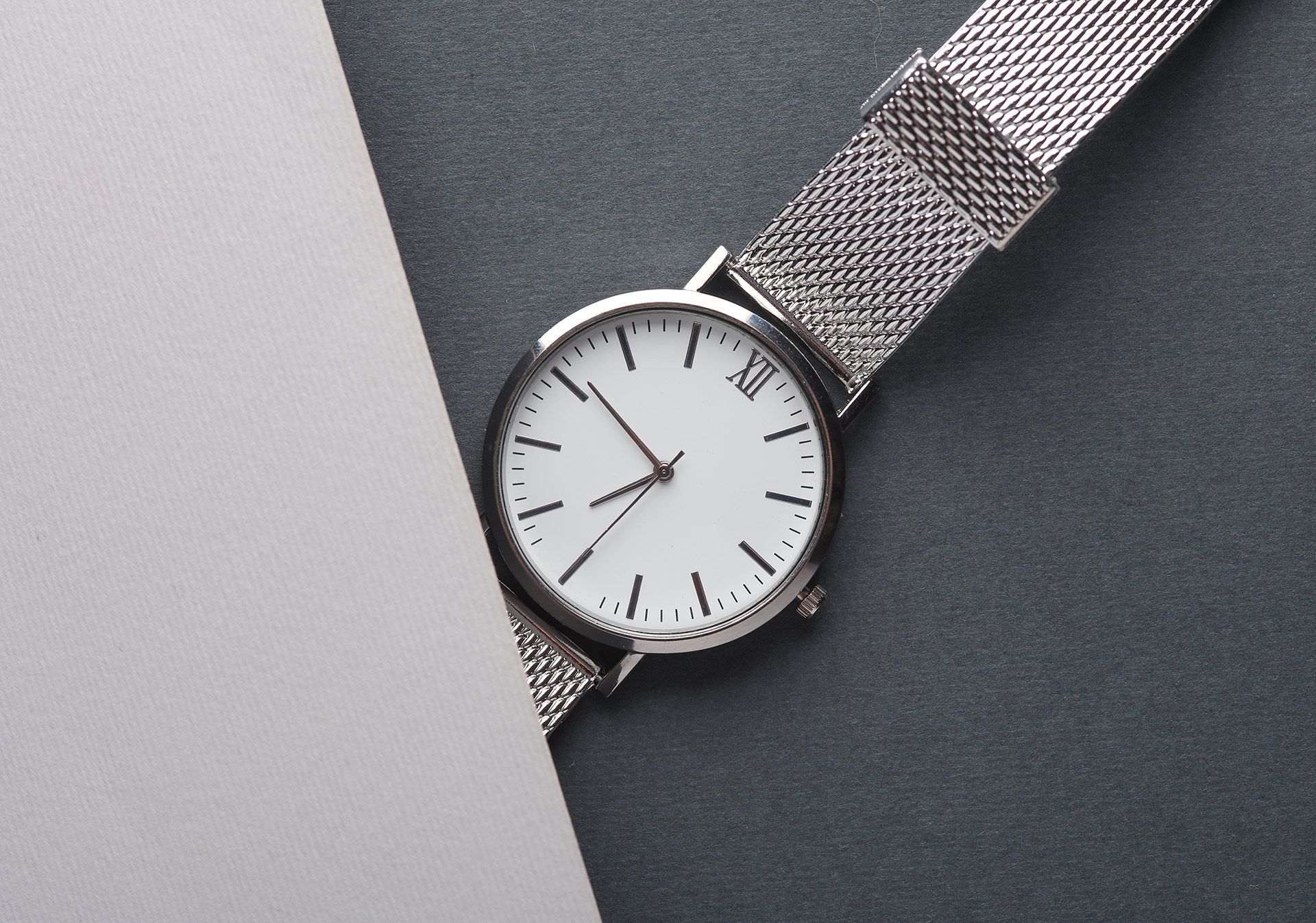 Silver wristwatch with white dial on a gray textured background