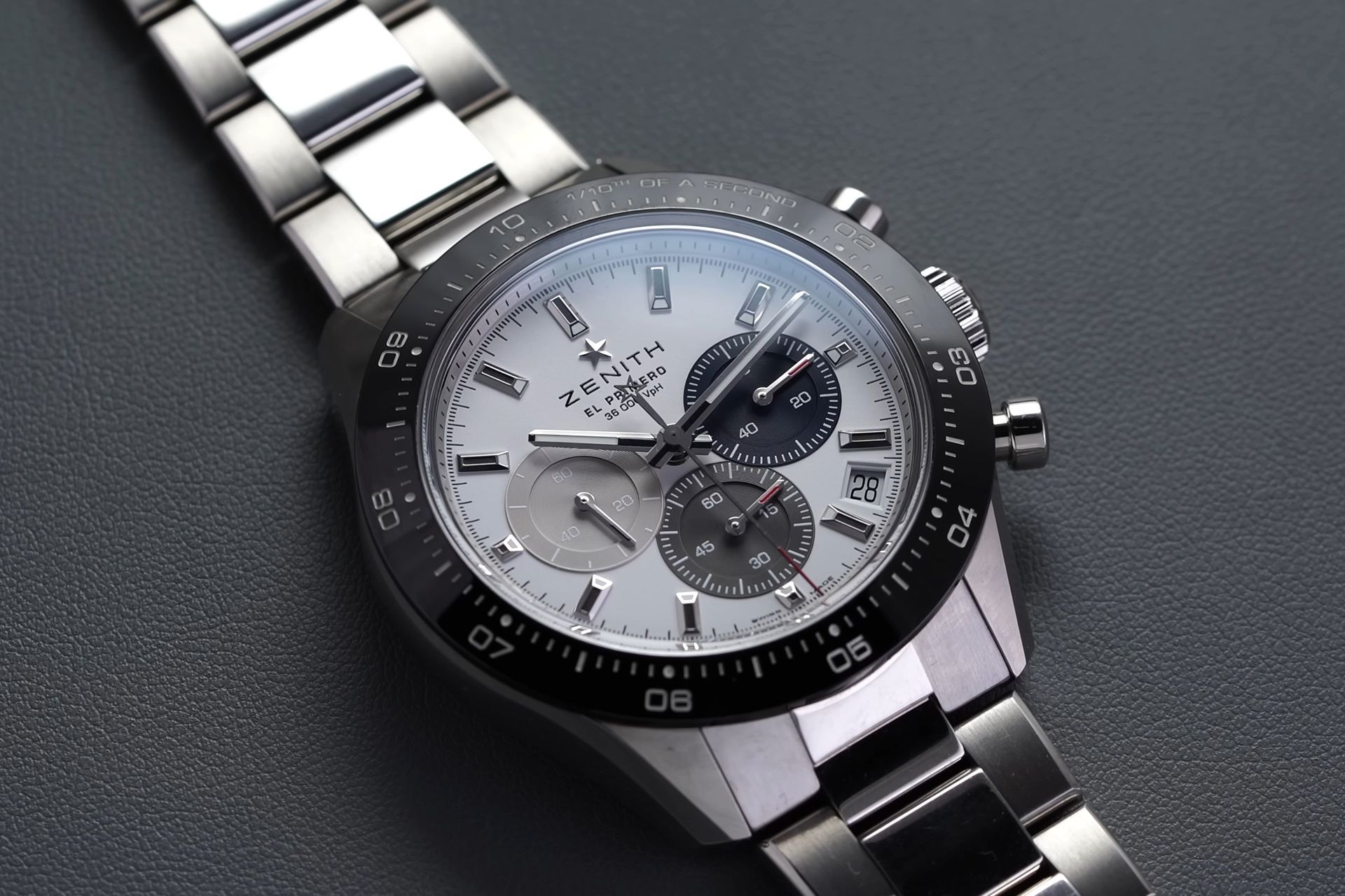 Silver chronograph wristwatch with black bezel on a dark surface