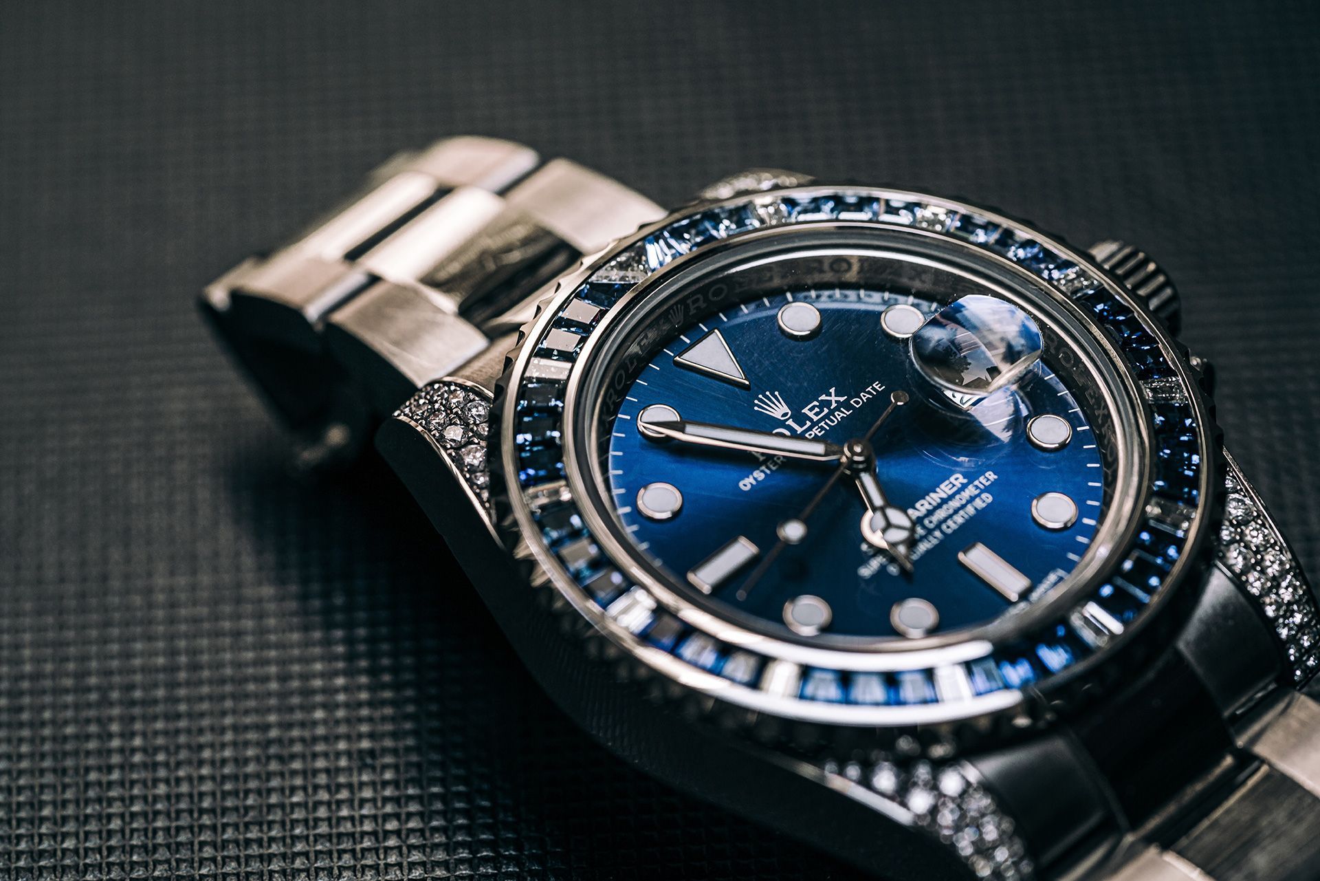 Blue-faced wristwatch with silver band on a dark textured surface
