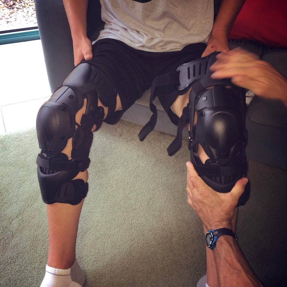 A Person Wearing Knee Pads is Being Held by Another Person — Gall Bros Medical in Brisbane, QLD