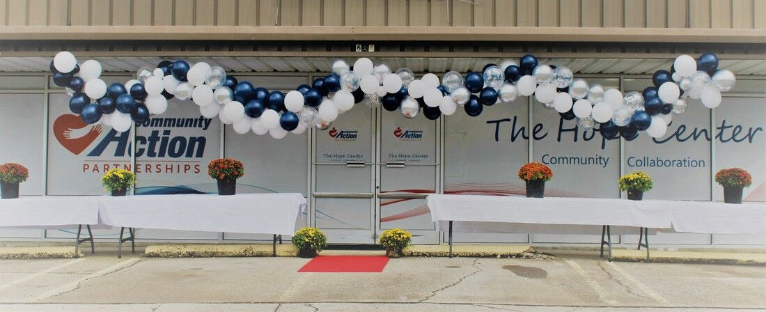 Decorated building entrance with blue and white balloons, a red carpet, and “The Fun Center” signage