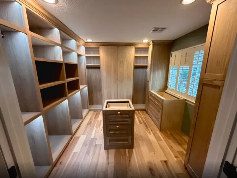 A walk in closet with lots of shelves and drawers