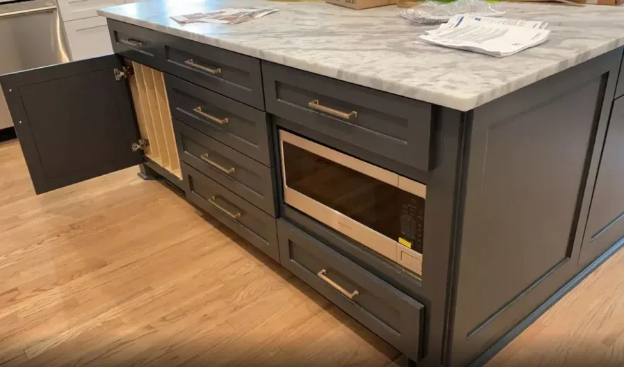 A kitchen island with a microwave oven and drawers.