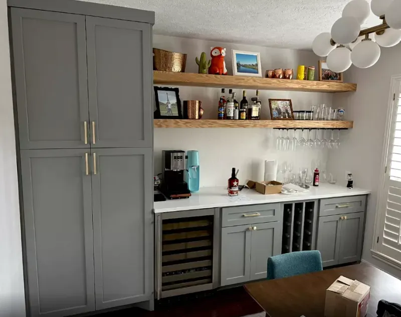 A kitchen with gray cabinets and a wine cooler