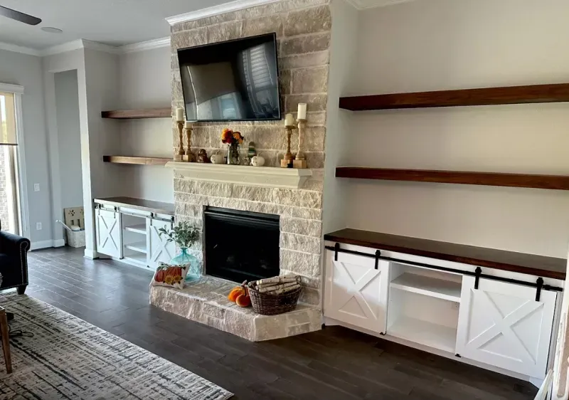 A living room with a fireplace , shelves , and a flat screen tv.