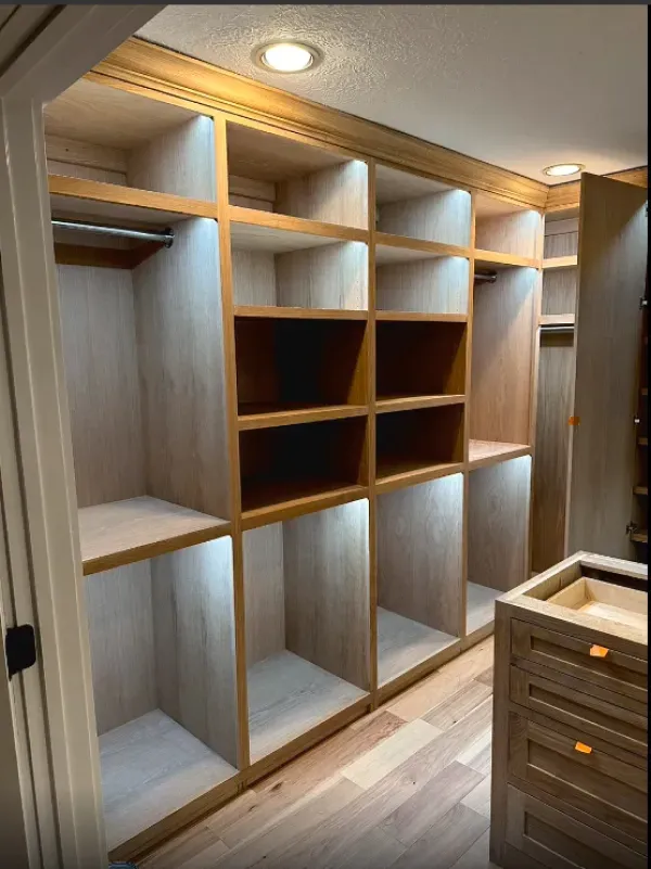 A walk in closet with wooden shelves and drawers