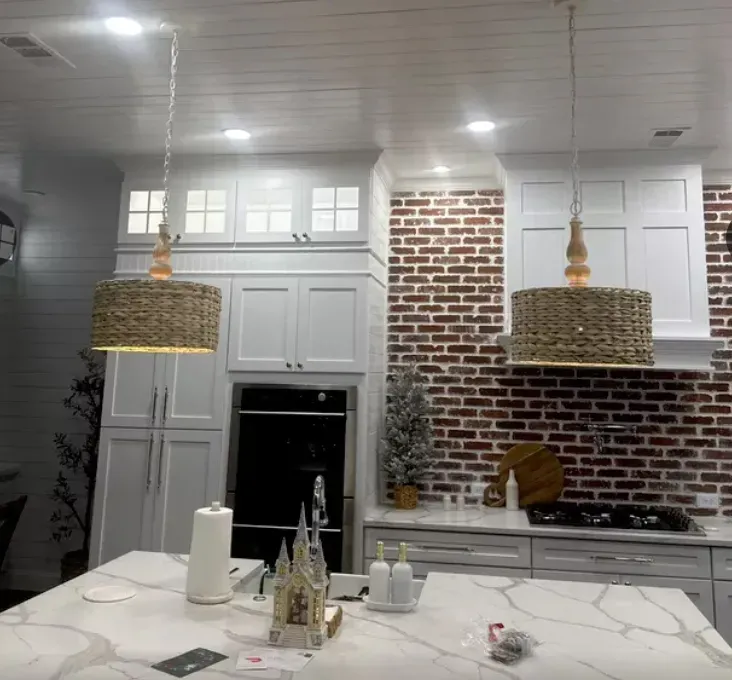 A kitchen with white cabinets and a brick wall